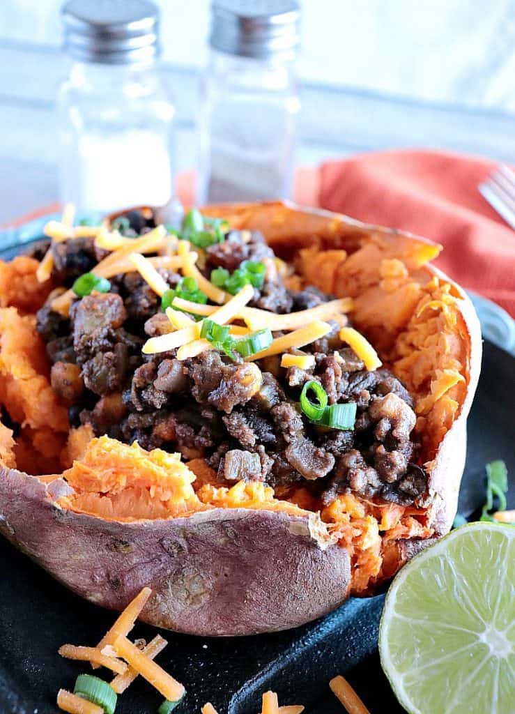 Vertical closeup photo of a Tex-Mex stuffed sweet potato with cheese and green onion.