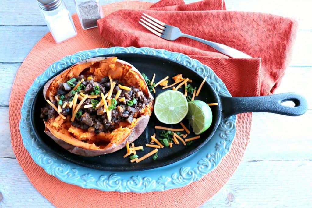 Overhead photo of Tex-Mex Stuffed Sweet Potatoes with Ground Beef & Beans on a blue platter with an orange napkin.