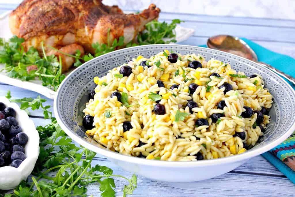 A blue bowl filled with Chilled Orzo Pasta Salad with Corn and Blueberry