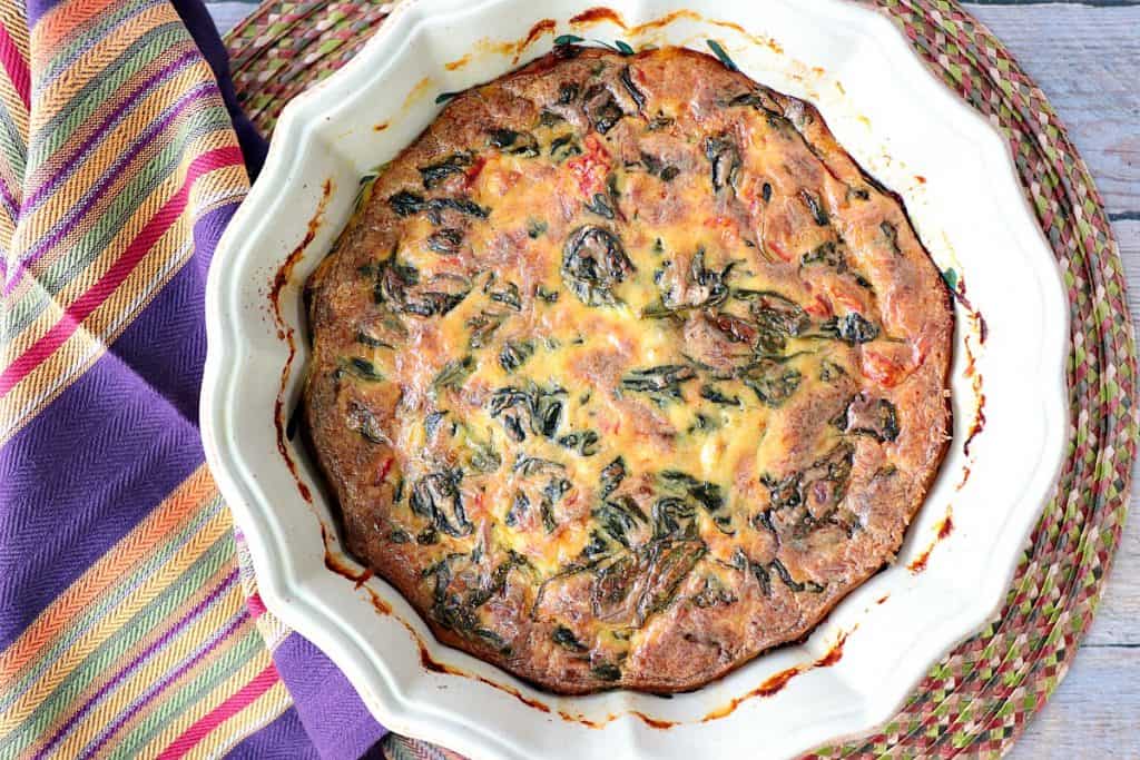 Overhead picture of creamed spinach casserole with a multi-colored napkin on the side.