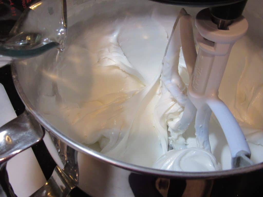 Royal icing in a bowl and adding water to thin the consistency.