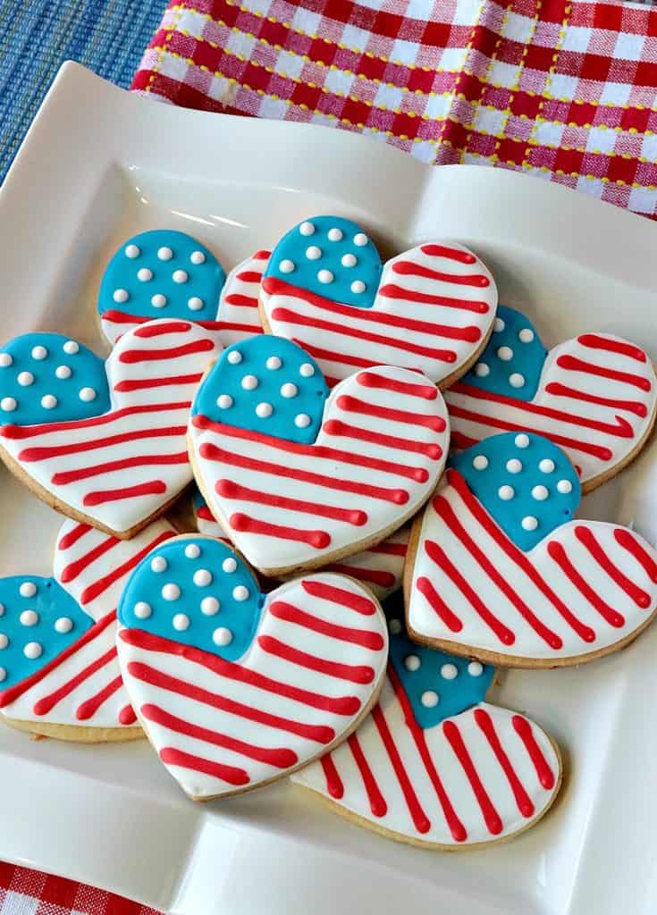 A white plate filled with red, white, and blue American flag heart cookies.