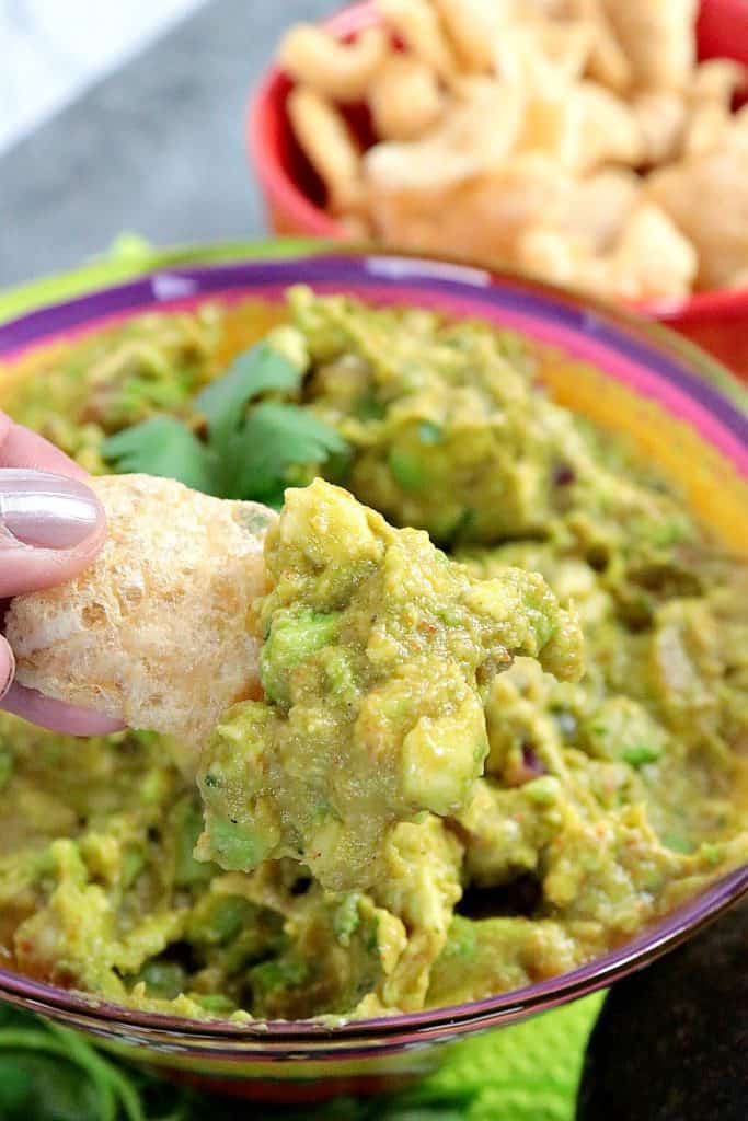 Closeup picture of guacamole on a pork rind chip.