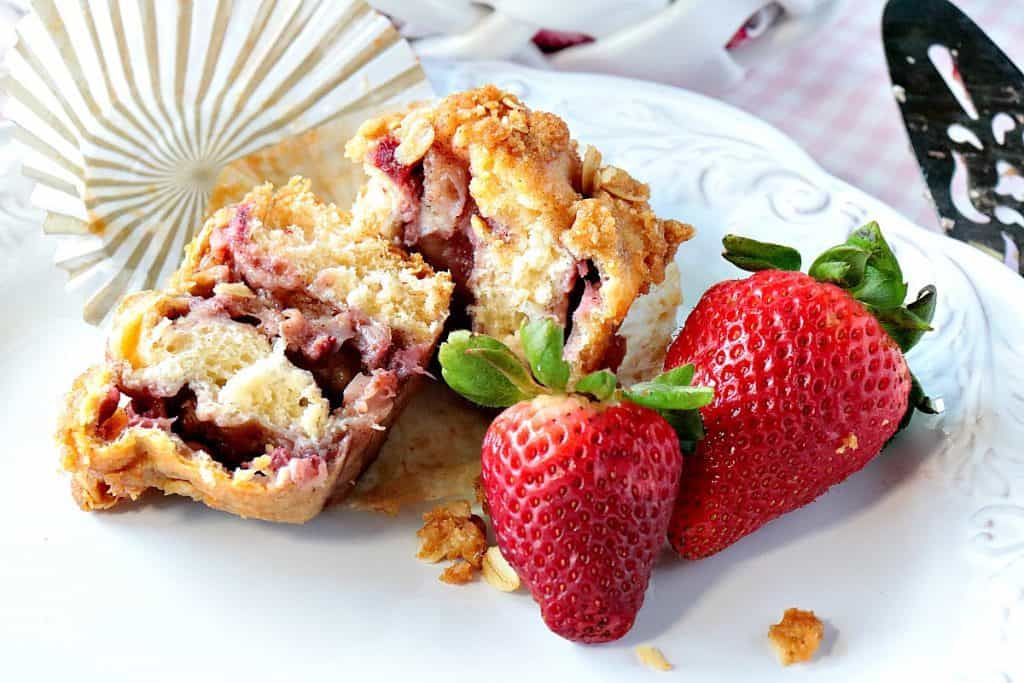 A closeup of the inside of a strawberry crescent muffin on a white plate with strawberries.