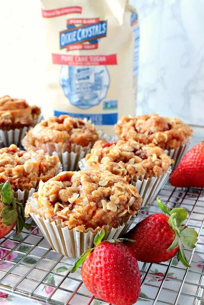 Closeup vertical photo of a bunch of strawberry crescent muffins on a wire rack with fresh strawberries as garnish.