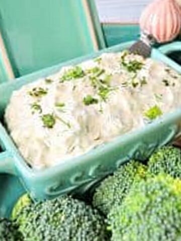 Homemade Boursin Cheese in a blue dish with broccoli in front of it.