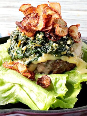 A ground beef burger topped with lemon creamed spinach and radish chips.