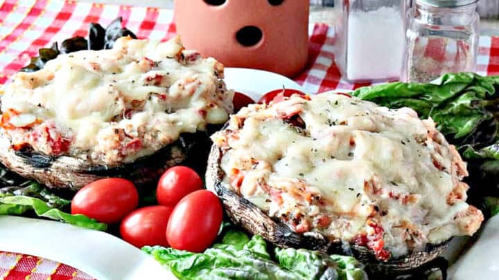 Two Chicken Parmesan Stuffed Portobellos on a plate with lettuce and tomatoes.