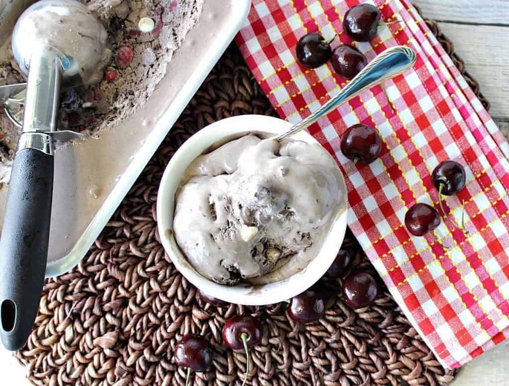 Overhead photo of a small dish of chocolate ice cream with cherries and white chocolate.