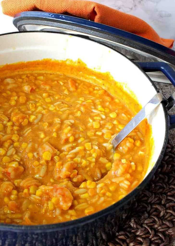 A vertical closeup photo of the inside of a Dutch oven filled with Pumpkin Shrimp and Orzo Chowder with a ladle and and orange napkin. Comfort food soups, stews, and chowders recipe roundup.