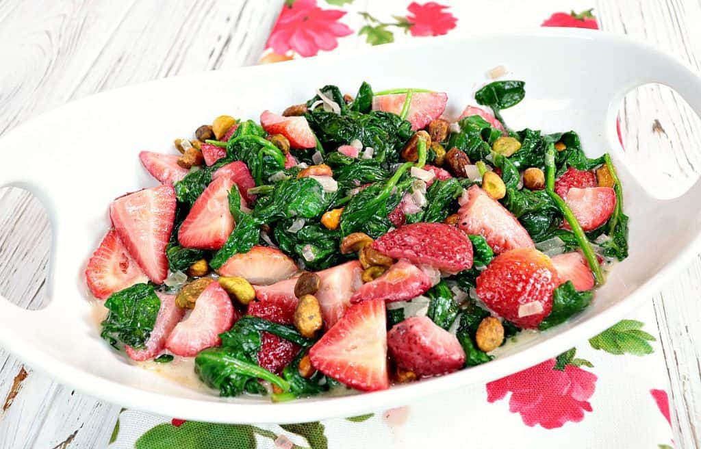 A white bowl filled with Sauteed Creamed Spinach and Strawberries.