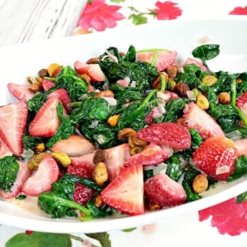 A white bowl filled with Sauteed Creamed Spinach and Strawberries.