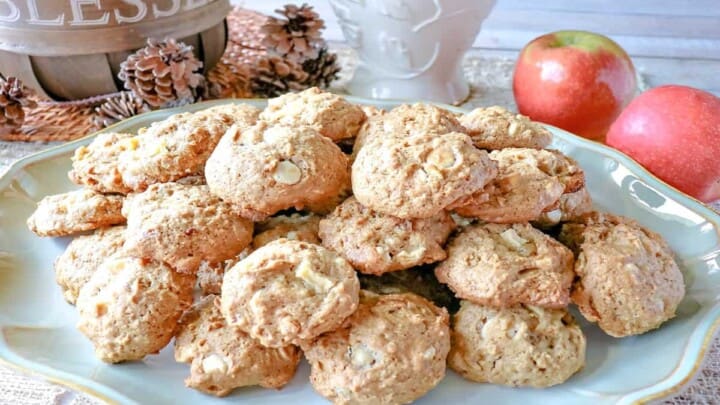 A platter filled with Apple Oatmeal Cookies with a basket in the background and some fresh apples.