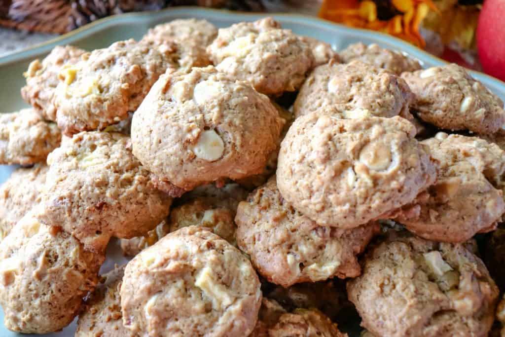  A closeup horizontal photo of a pile of Apple Oatmeal Cookies with white chocolate and pecans 