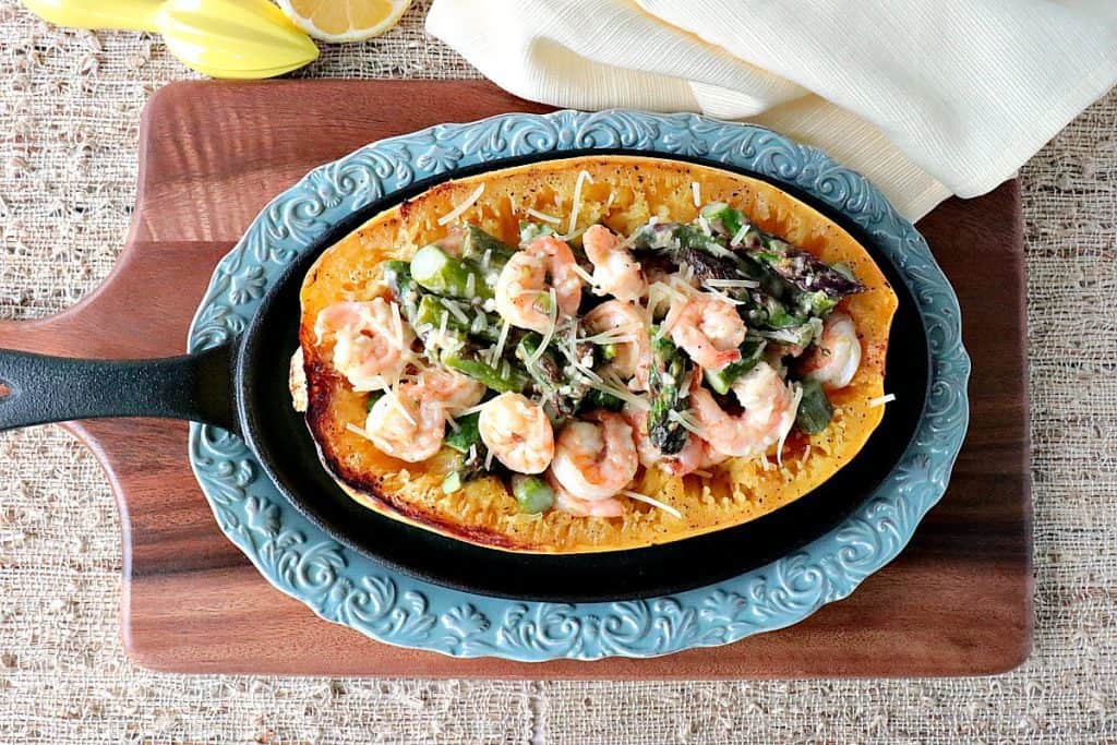 Overhead photo of spaghetti squash shrimp scampi on a blue plate with a lemon and a napkin.