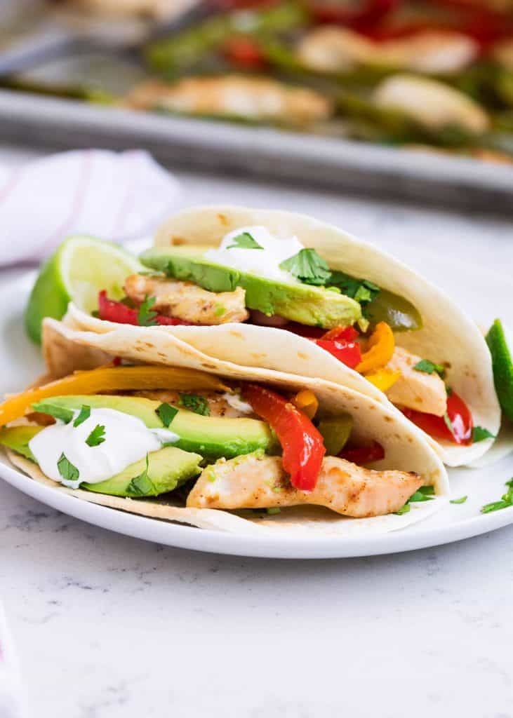 Easy Weeknight Dinner Recipes. Chicken Tacos on a plate with avocado, peppers, and limes.