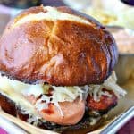 Knockwurst Sandwich on a tray with a pretzel bun and sauerkraut.