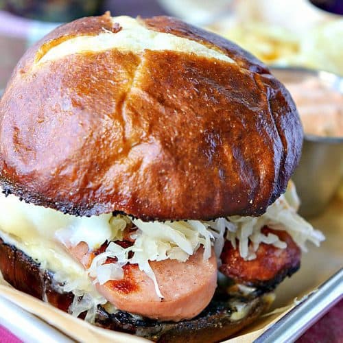 Knockwurst Sandwich on a tray with a pretzel bun and sauerkraut.