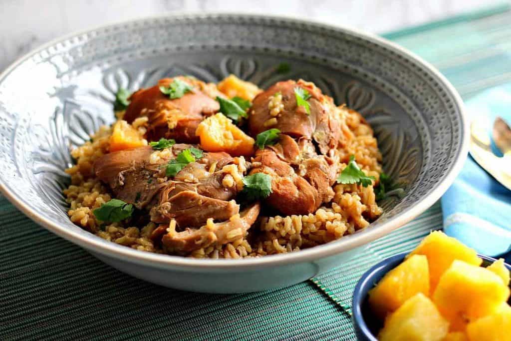 Slow Cooker Hawaiian Pineapple chicken thighs in a blue bowl over rice