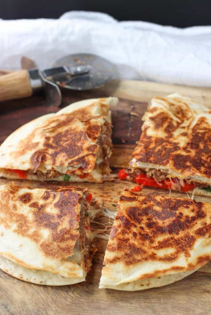 Easy Weeknight Dinner Recipes. Four sliced quesadillas with a pizza cutter in the background.