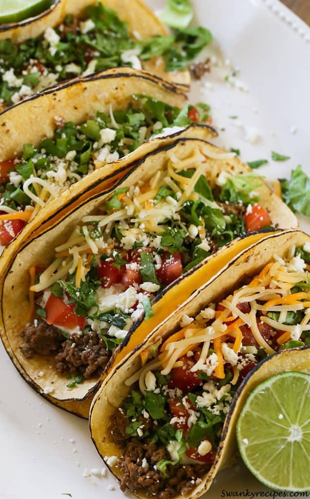 Easy Weeknight Dinner Recipes. Tacos on a white platter with cheese, tomatoes, and ground beef.