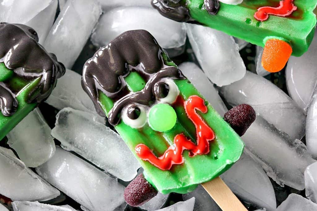 Closeup photo of a frozen Halloween pudding pop with a scary face and gumdrop nose.