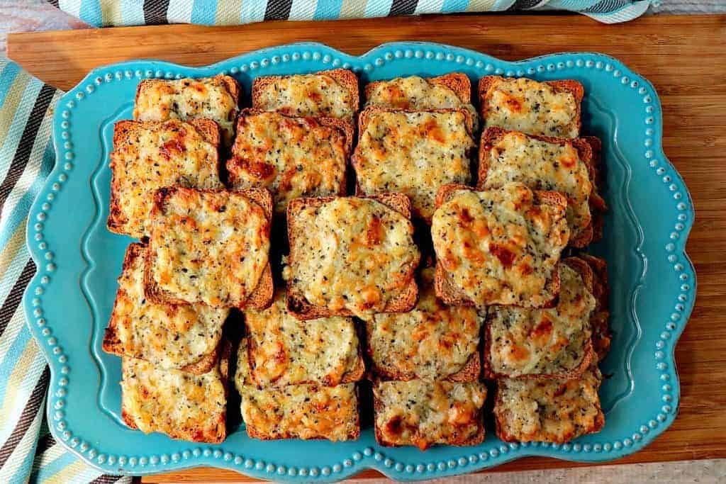 A plate full of Parmesan onion appetizer squares with a blue striped napkin. New Year's eve appetizers and drinks recipe roundup.