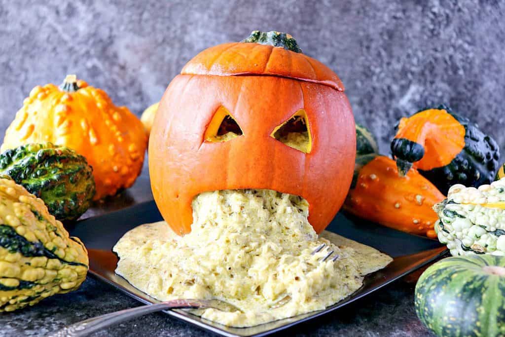 Horizontal Halloween photo of a jack-o-lantern on a black plate with squash and vomit.