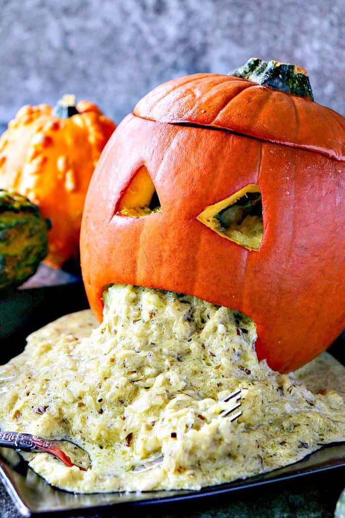 Gross picture of a puking pumpkin with assorted squash in the background.