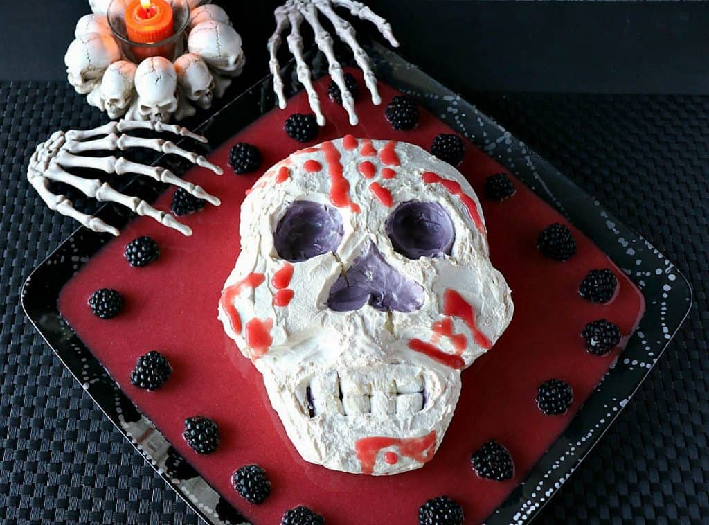 Overhead photo of a Swiss meringue skill with berry puree and skeleton hands.