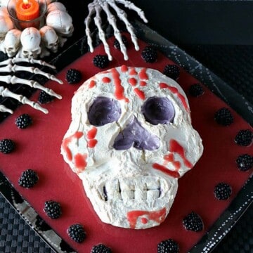 Overhead photo of a Swiss meringue skill with berry puree and skeleton hands.