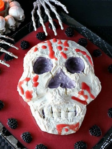 Overhead photo of a Swiss meringue skill with berry puree and skeleton hands.