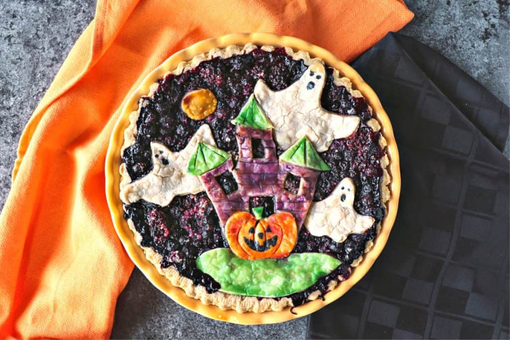 Overhead photo of a Halloween pie with orange and black napkins.