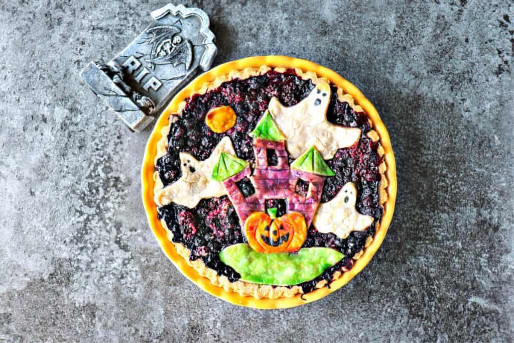 Horizontal overhead photo of a Boo Berry Pie on a grey background with a tombstone.