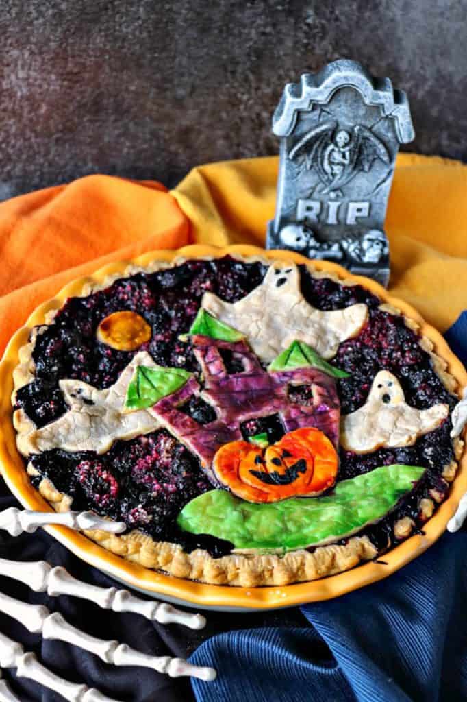 Vertical close up image of a Halloween pie with ghosts, haunted house, and pumpkins. Boo berry pie.