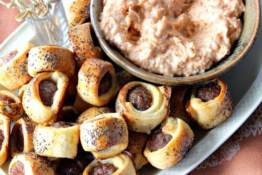 A plate full of bratwurst bites with sauerkraut dipping sauce in a bowl.
