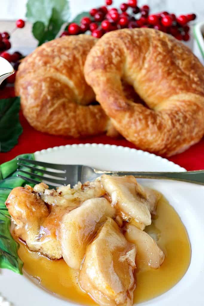 Vertical closeup image of a serving of apple croissant breakfast bake on a holiday plate with a fork.