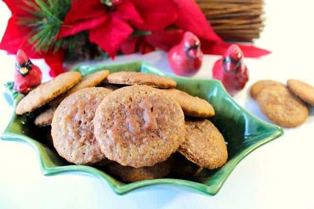 A closeup photo of soft gingerbread cookies in a holly berry dish with a cardinal for a Christmas cookie recipe roundup.
