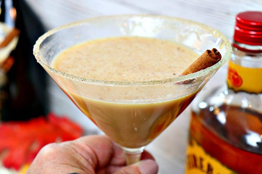 Closeup photo of a Pumpkin Spice Martini with a cinnamon stick and a sugar cinnamon rim.