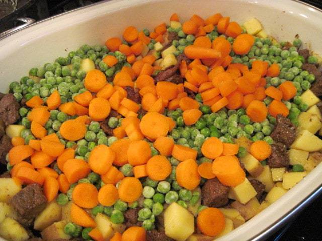 A large roaster filled with the ingredients for beef stew.