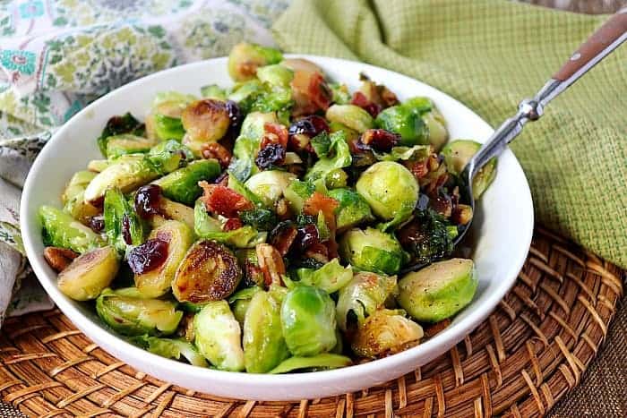 Sauteed Brussels Sprouts in a white bowl with a spoon.