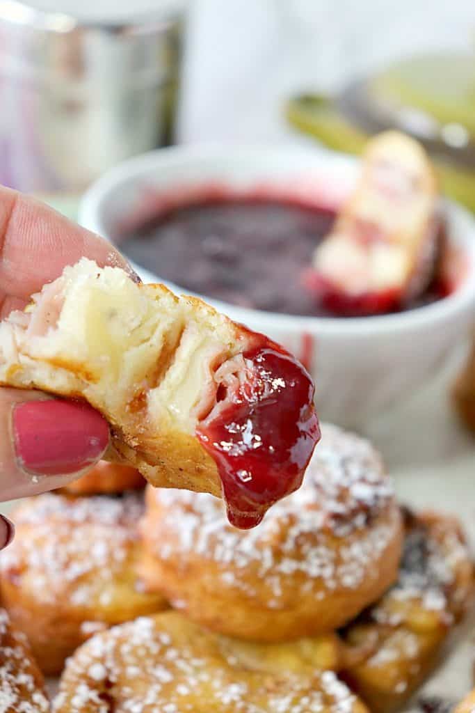 Closeup bite of Monte Cristo Tortilla Roll Ups dipped in Raspberry Sauce. New years eve appetizers and drinks recipe roundup.