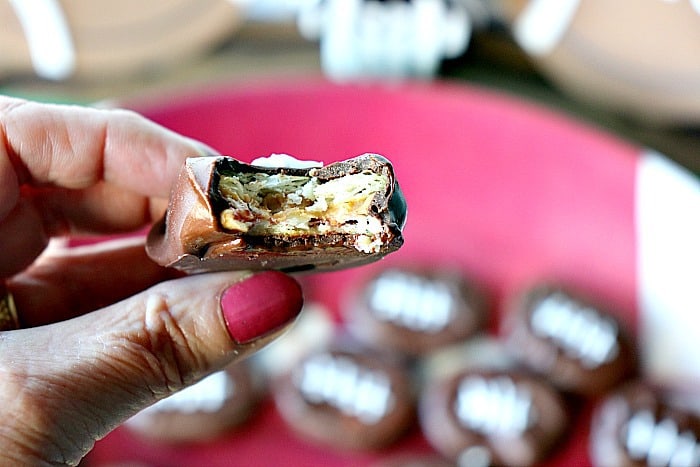 A closeup photo of a hand holding a  Peanut Butter and Jelly Chocolate Football with a bit take out.