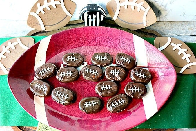 An overhead photo of Peanut Butter and Jelly Chocolate Footballs on a football plate with one missing.