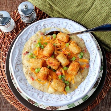 Overhead shot of tater tot chowder in a white bowl with a plaid charger.