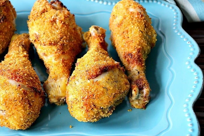 Closeup of Air fryer chicken drumsticks on a blue scalloped plate.