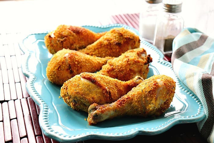 Air fryer chicken drumsticks on a blue plate with a salt and pepper shaker.