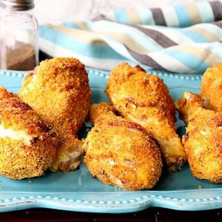 Six chicken drumsticks sitting on a blue plate with a napkin.