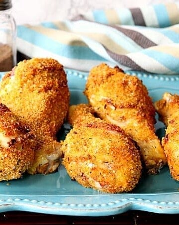 Six chicken drumsticks sitting on a blue plate with a napkin.