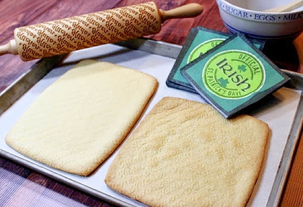 Two rolled and baked slabs of Traditional Irish Shortbread on a baking sheet with a rolling pin.